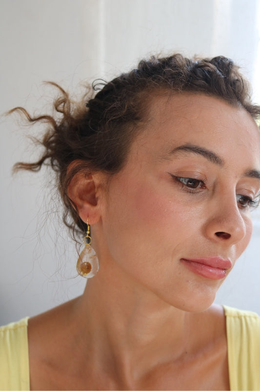 Woman with styled hair and earrings against a neutral background